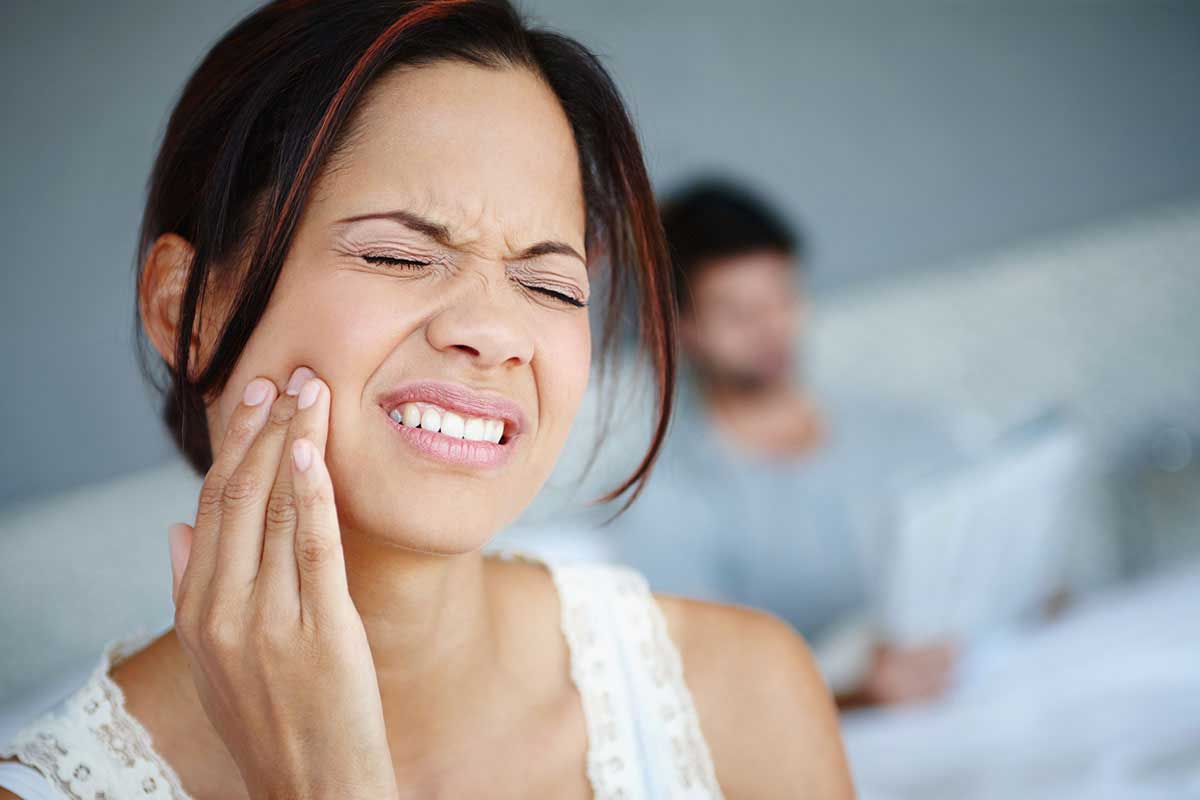 woman holding her mouth in need of an emergency dentist